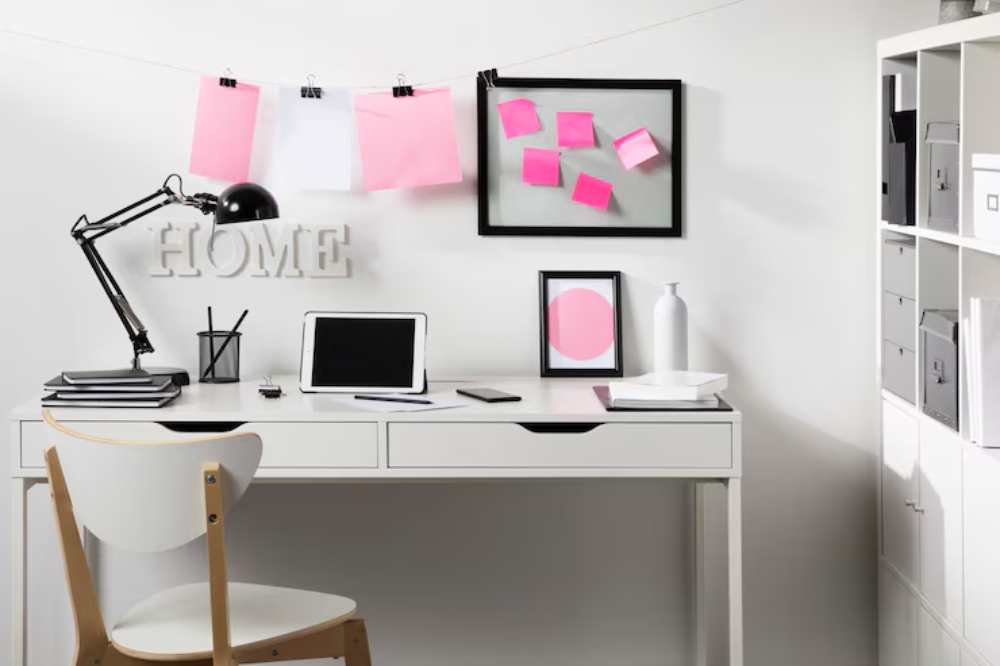 A modern study space featuring a white desk, lamp, tablet, notes, and decorative items against a minimalist backdrop.