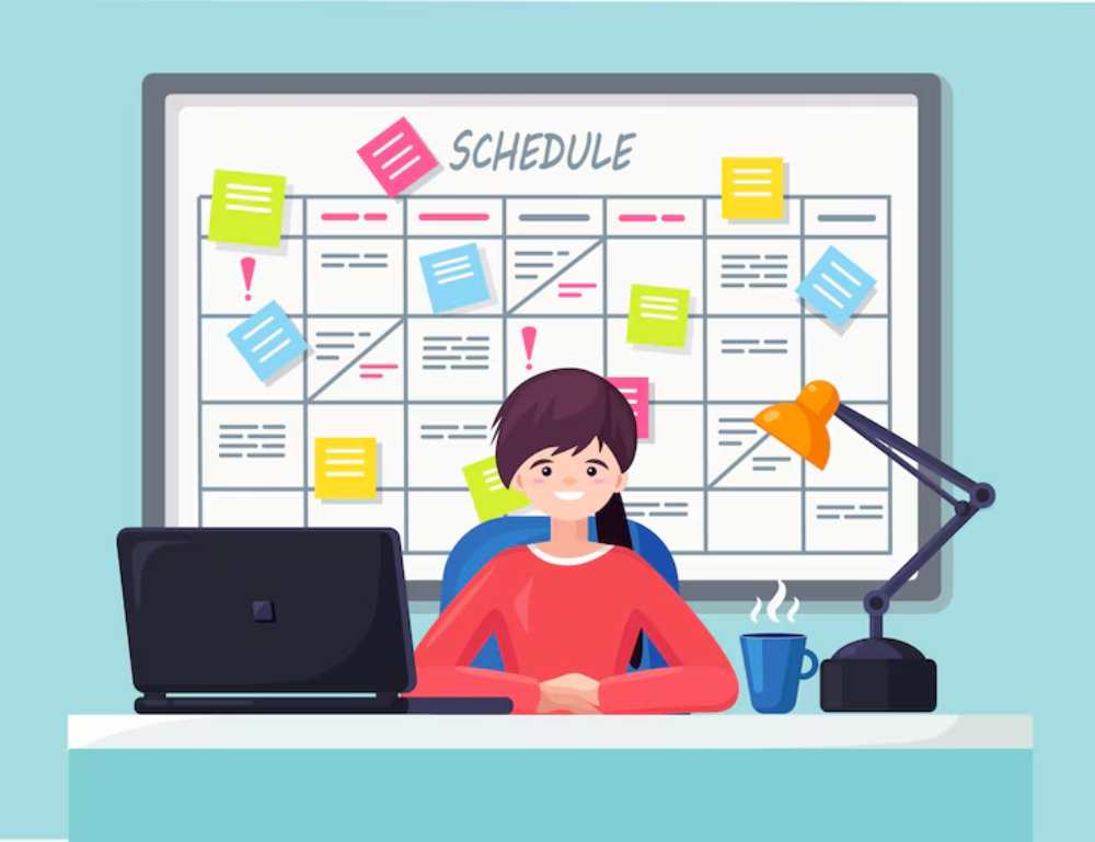 A smiling person sits at a desk with a laptop, coffee mug, and desk lamp, in front of a colorful schedule board filled with notes.
