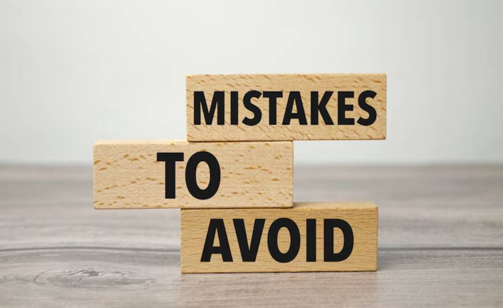 Wooden blocks stacked to read 'MISTAKES TO AVOID,' set against a blurred background, conveying a message about caution and awareness.